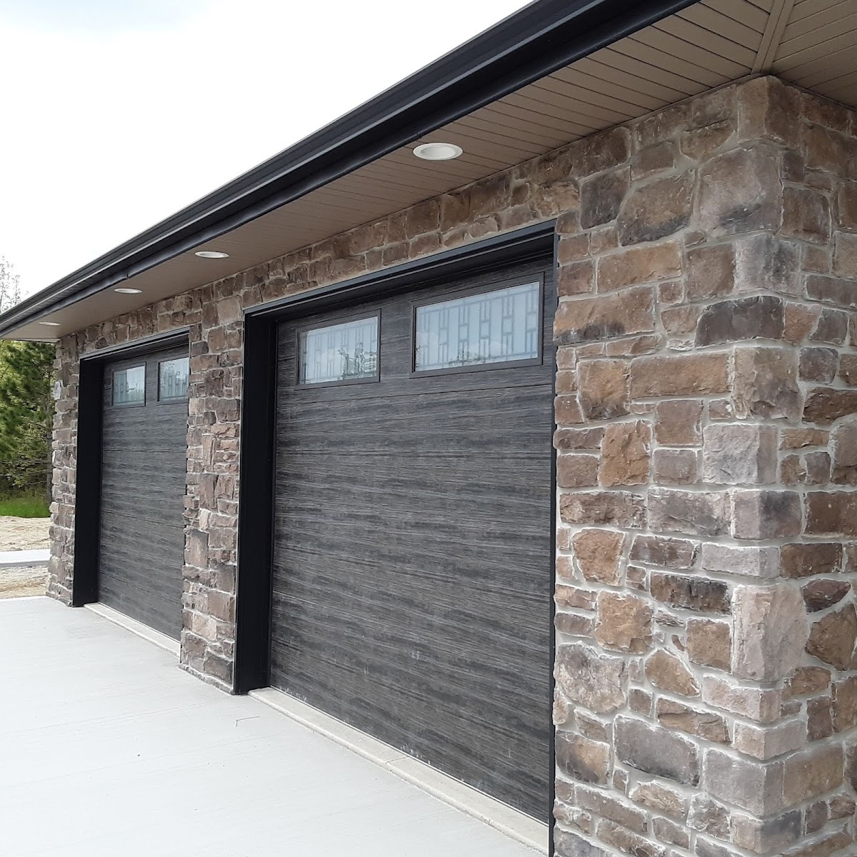 A completed S&W Electric job. Finished garage exterior with custom dark doors set in stone veneer, Columbia City Indiana